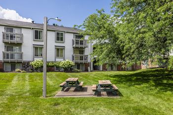 A grassy area with a picnic table in front of a building